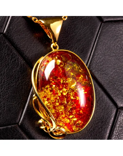 Ciondolo in ambra rosso cognac: gemma con inclusioni dorate, eleganza senza tempo.