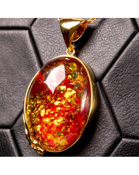Ciondolo in ambra rosso cognac: gemma con inclusioni dorate, eleganza senza tempo.