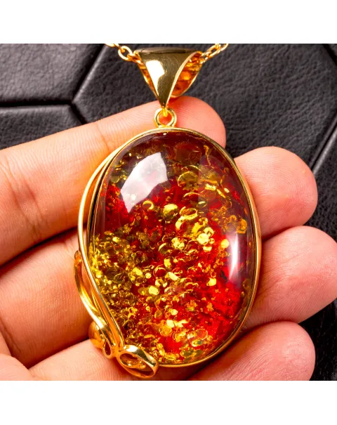 Ciondolo in ambra rosso cognac: gemma con inclusioni dorate, eleganza senza tempo.