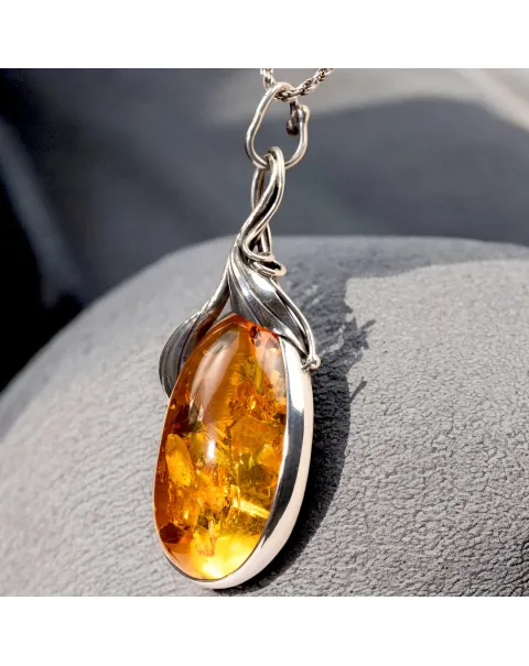 Ciondolo in argento con ambra color miele e inclusioni a forma di petali: eleganza naturale e armonia.