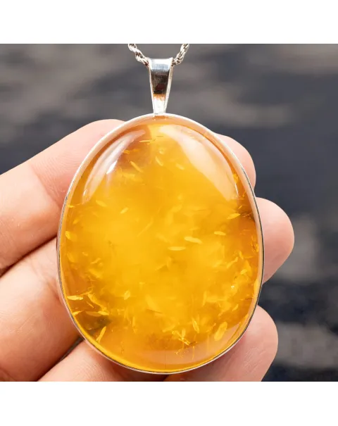 Ciondolo in argento con ambra color miele: eleganza e protezione energetica.