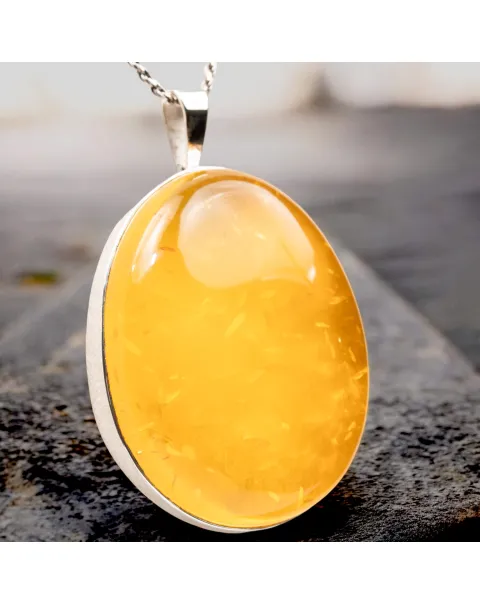 Ciondolo in argento con ambra color miele: eleganza e protezione energetica.