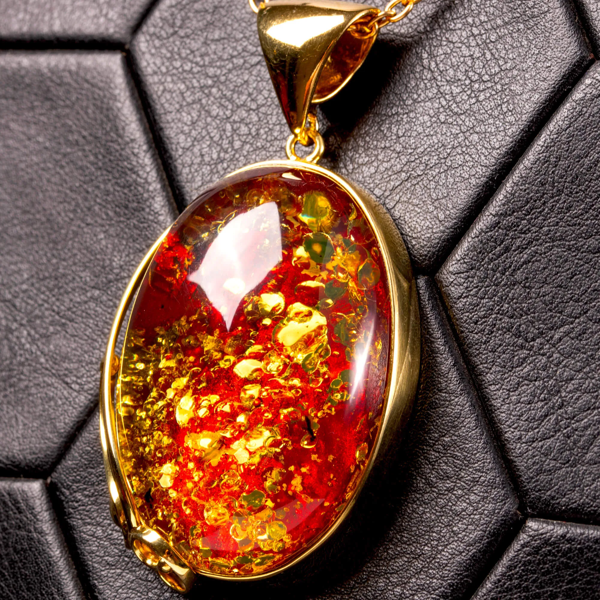 Ciondolo in ambra rosso cognac: gemma con inclusioni dorate, eleganza senza tempo.