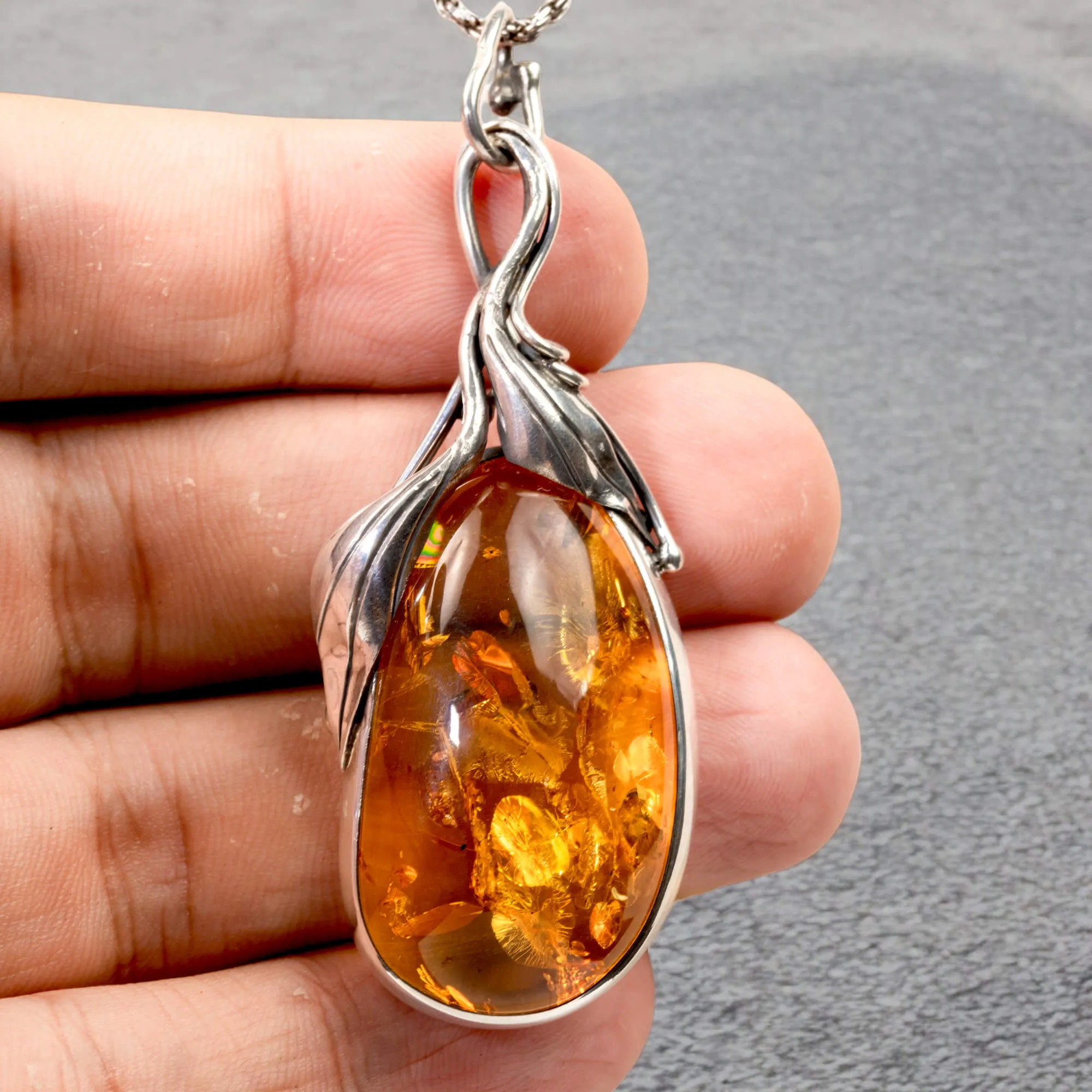 Ciondolo in argento con ambra color miele e inclusioni a forma di petali: eleganza naturale e armonia.
