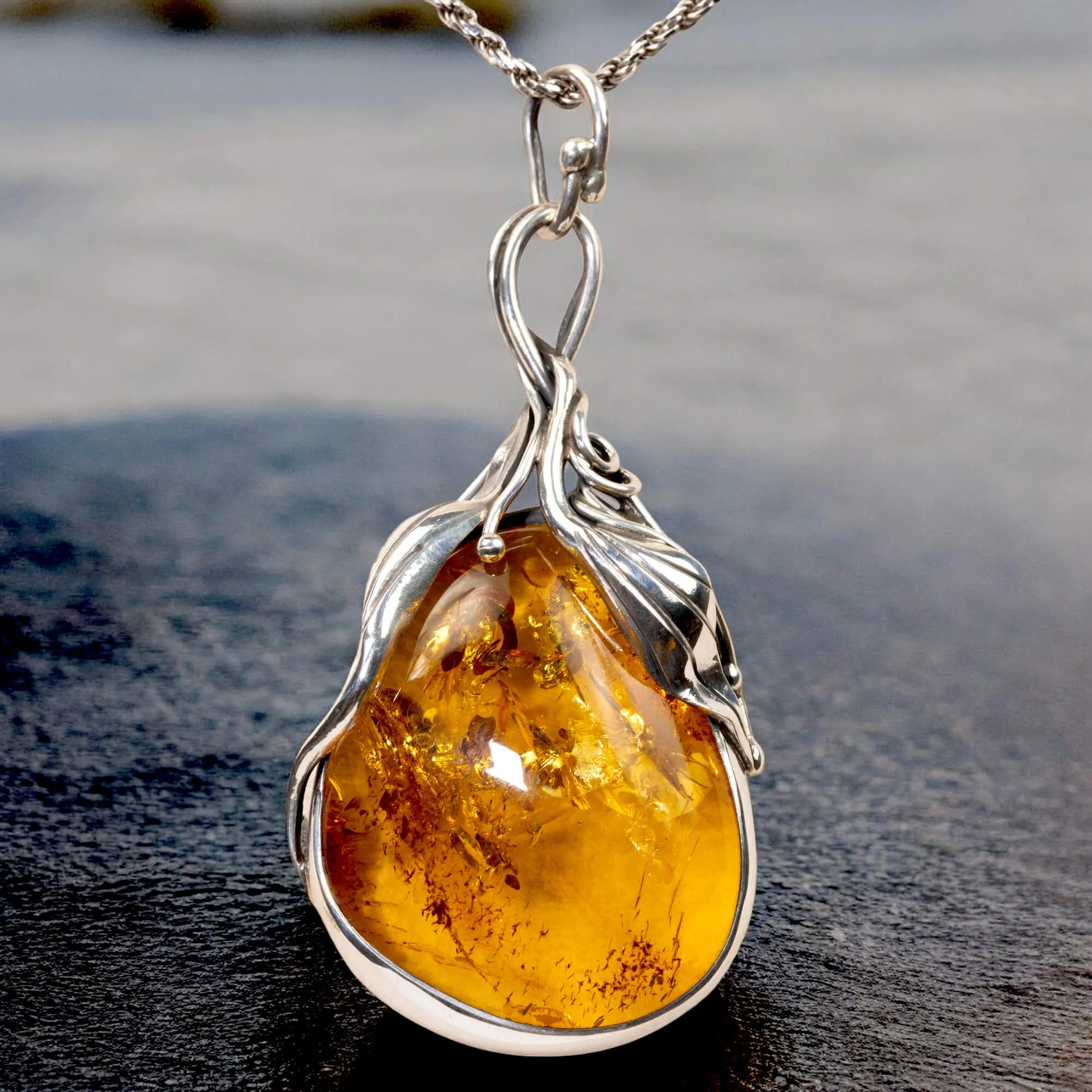 Ciondolo in argento con ambra color miele: fascino e protezione.