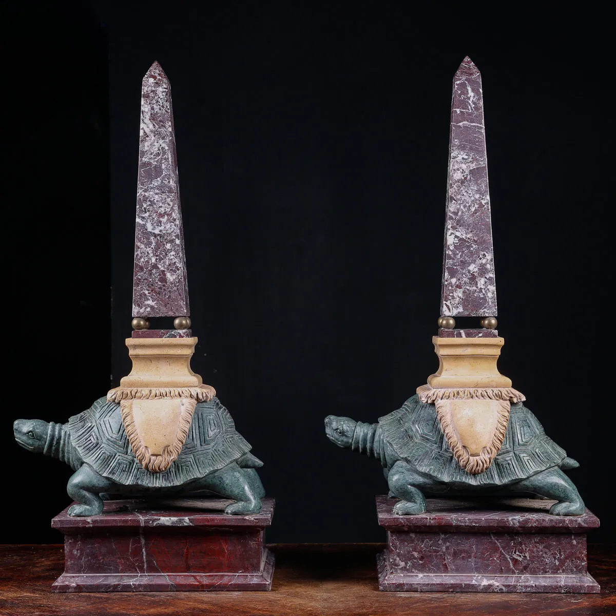 Coppia di obelischi in marmo con base scultorea a forma di tartaruga.
